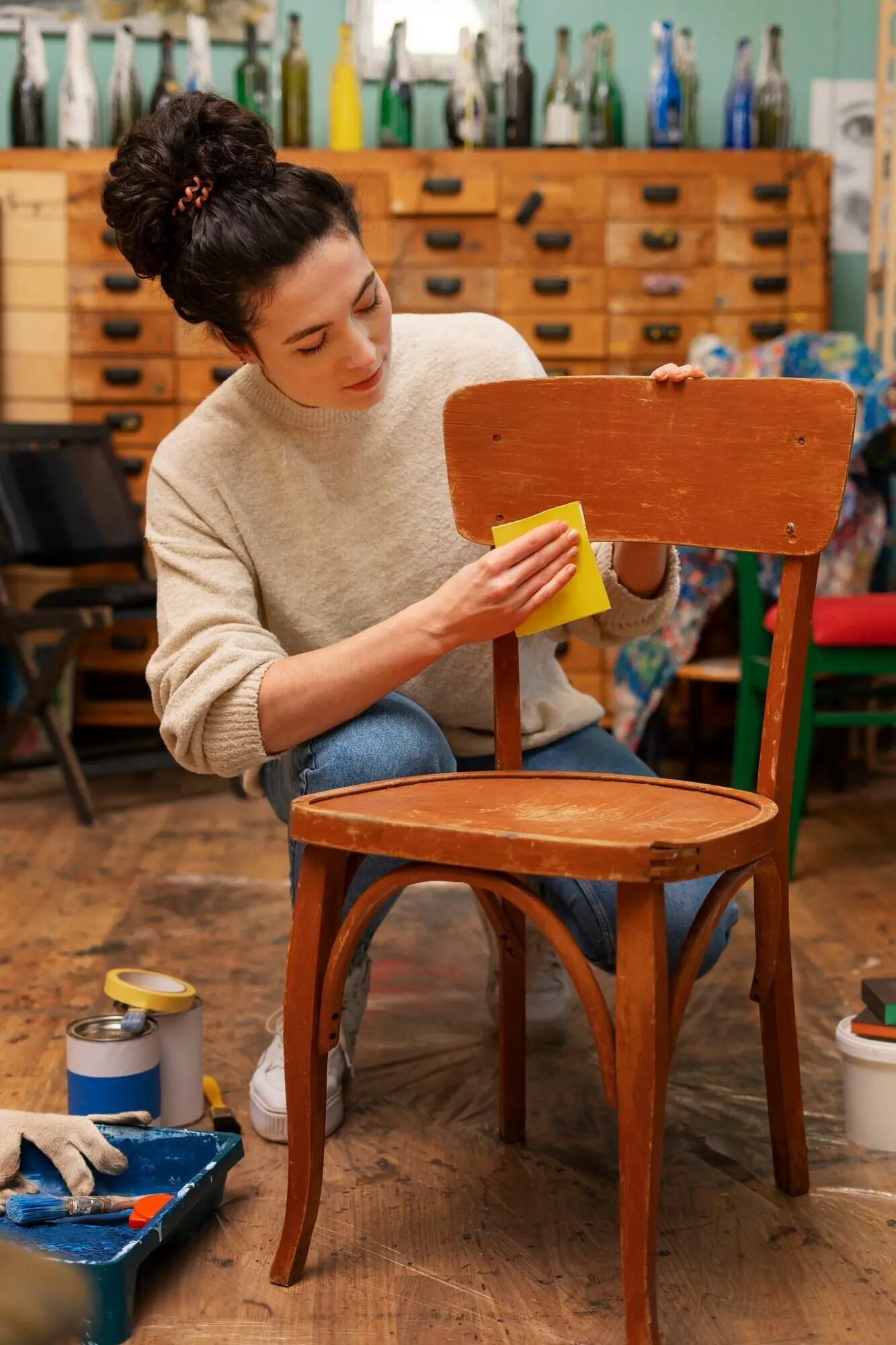 Vorderansicht einer Frau, die einen Holzstuhl restauriert.